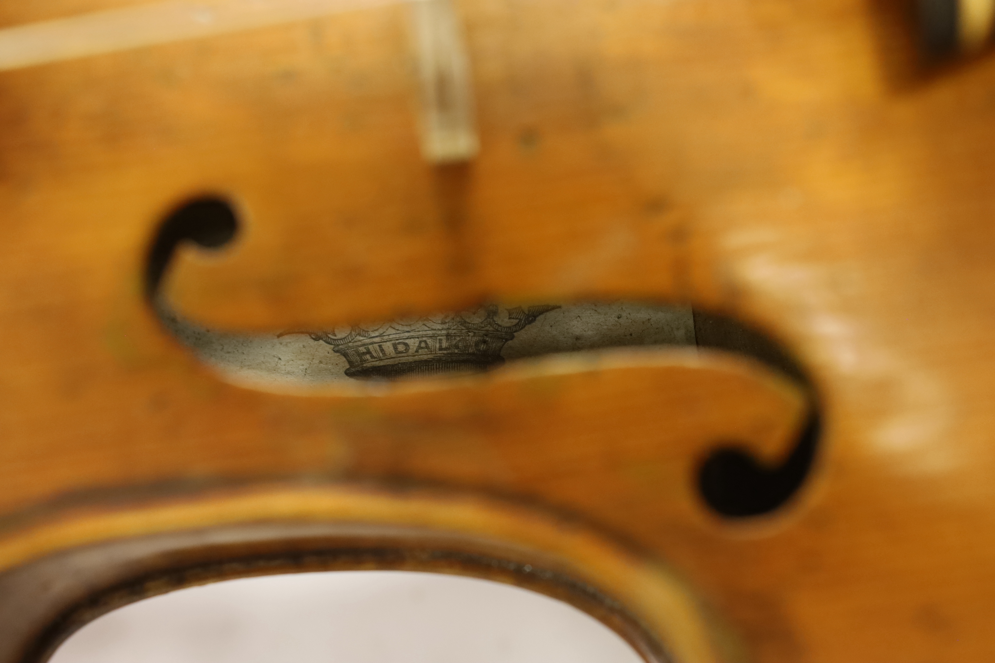 A late nineteenth century English violin by Hidalgo with a label inside the body showing a crown over Hidalgo, with a bow in an ebonised wooden case, body 36cm